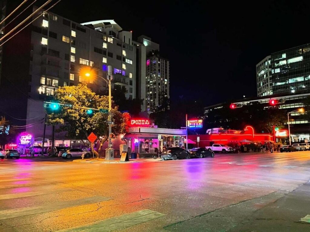 Neon signs and live music bars glowing along Austin’s 6th Street after sunset.