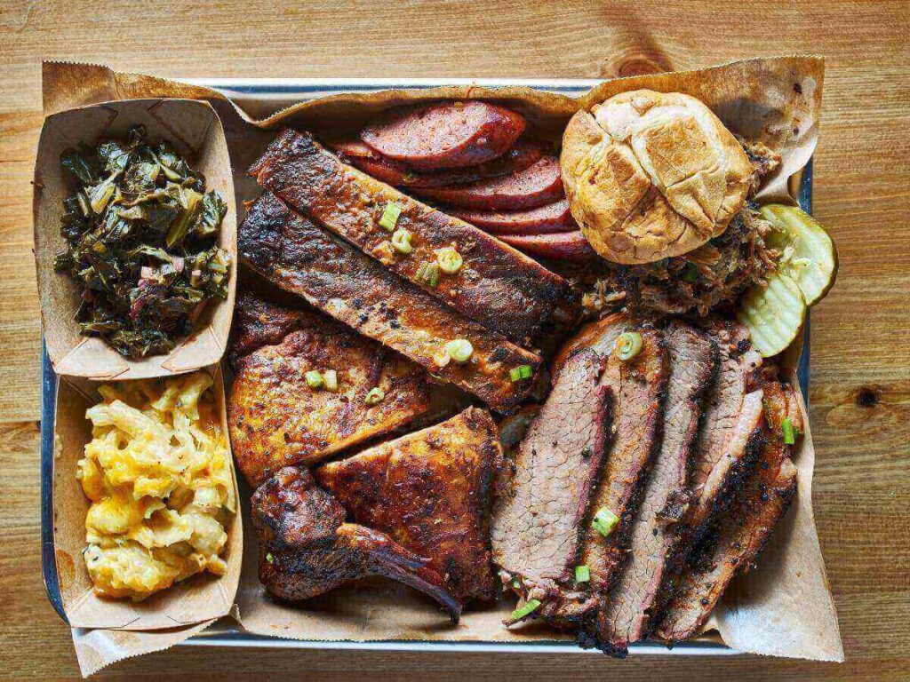 Tray of sliced brisket, ribs, and classic Texas barbecue sides at an Austin smokehouse