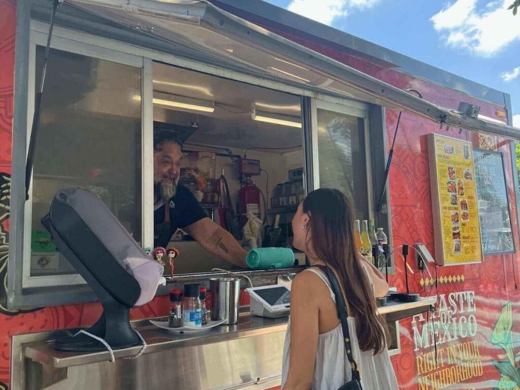 A cluster of Austin food trucks set up around picnic tables during golden hour