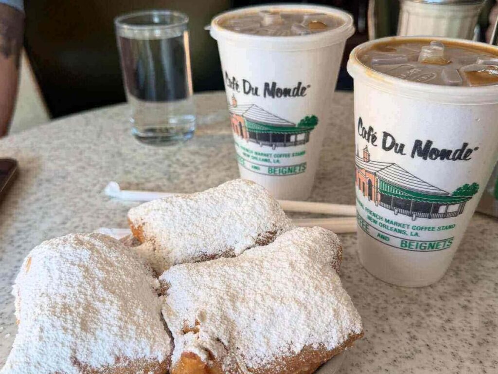 Fresh beignets covered in powdered sugar served with café au lait at a New Orleans café in the morning