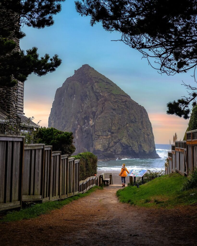 Coastal view of Haystack Rock at Cannon Beach with people walking along the shore