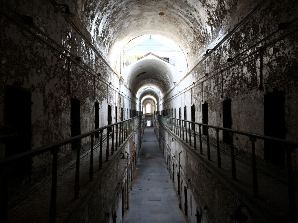A decaying corridor inside Eastern State Penitentiary with dramatic lighting
