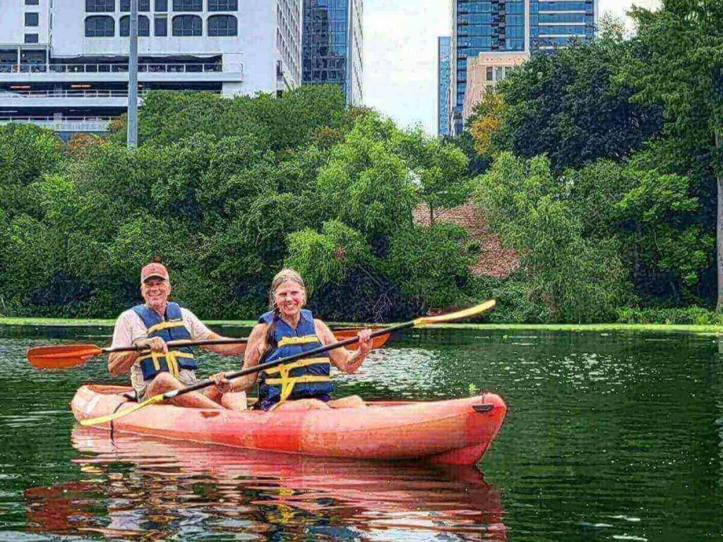 Kayaker paddling on Lady Bird Lake at sunrise with downtown Austin reflecting on the water
