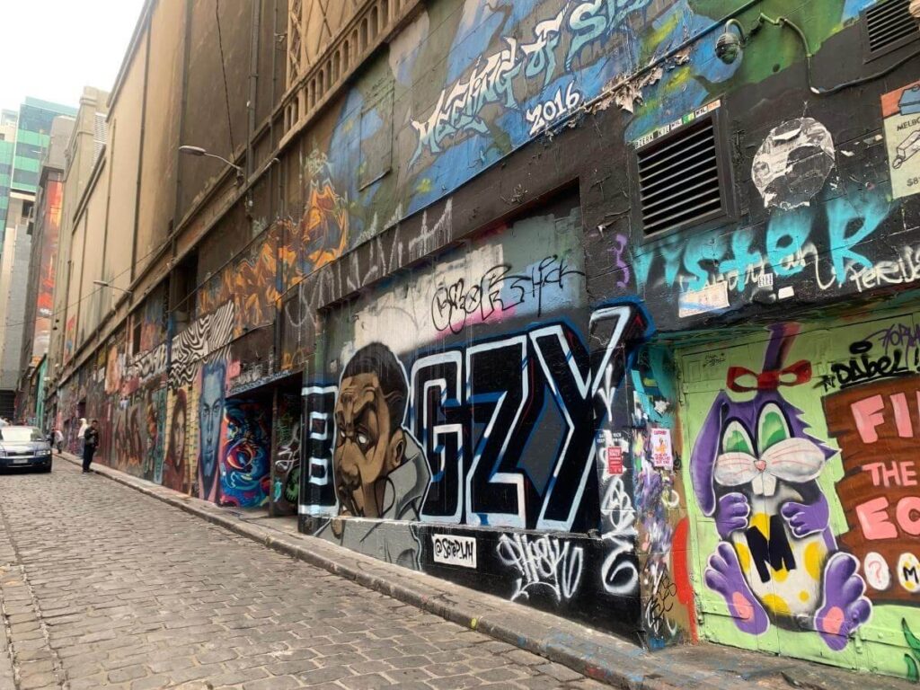 Colorful large-scale mural on a warehouse wall in RiNo with a person pausing to look.