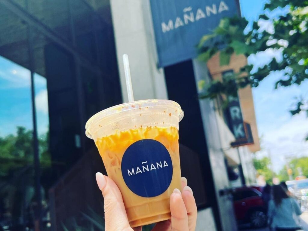 Early morning view of South Congress with people walking past cafés and colorful storefronts