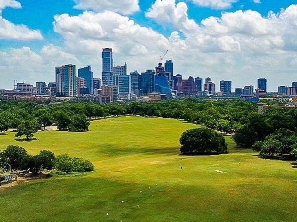 Wide open lawn at Zilker Park with the Austin skyline peeking through the trees