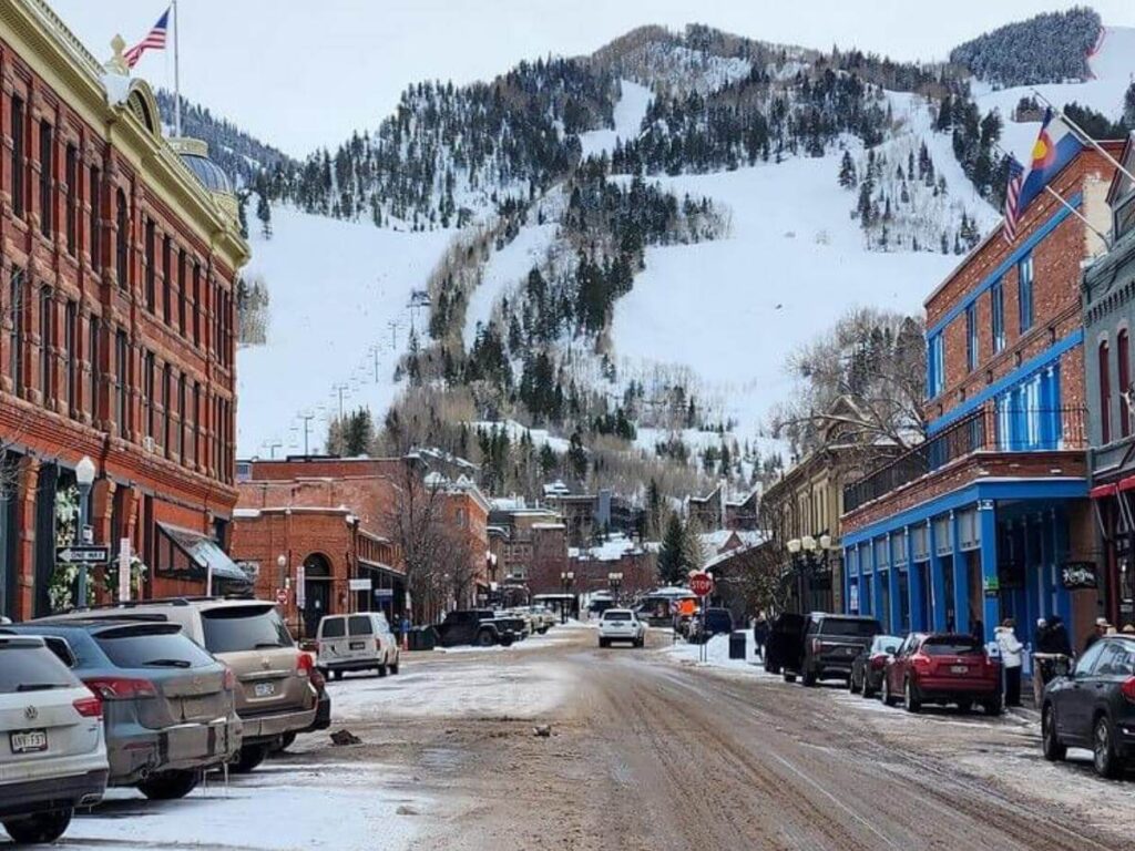 Pedestrian street in downtown Aspen with cafés, shops and mountain backdrop in late afternoon light