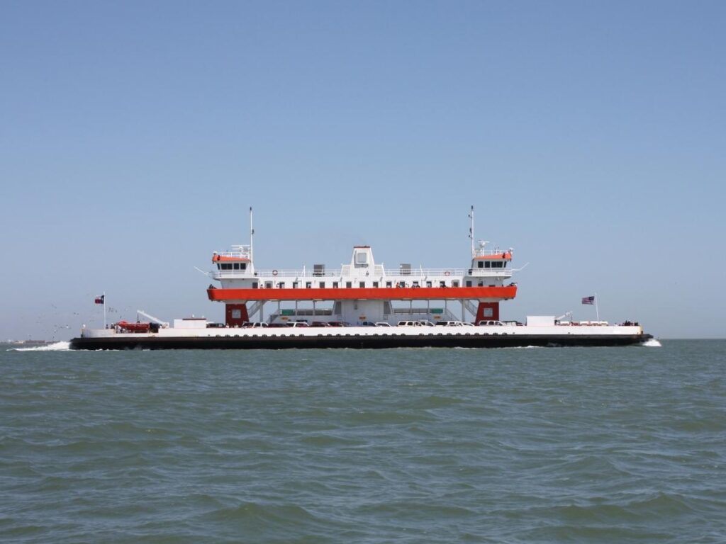 Galveston–Bolivar ferry crossing the channel with dolphins swimming alongside.