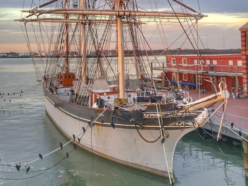 The 1877 Tall Ship ELISSA docked at Galveston harbor with sails folded and historic rigging..