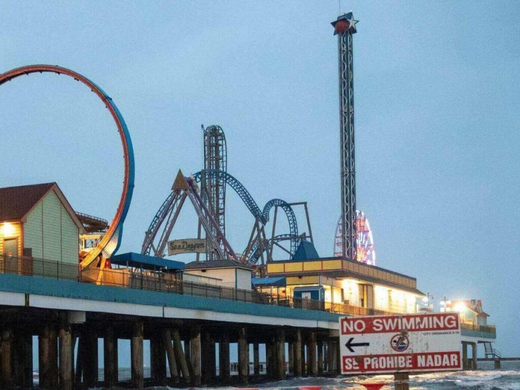Quiet natural shoreline at Galveston Island State Park with grassy dunes and calm Gulf waves.