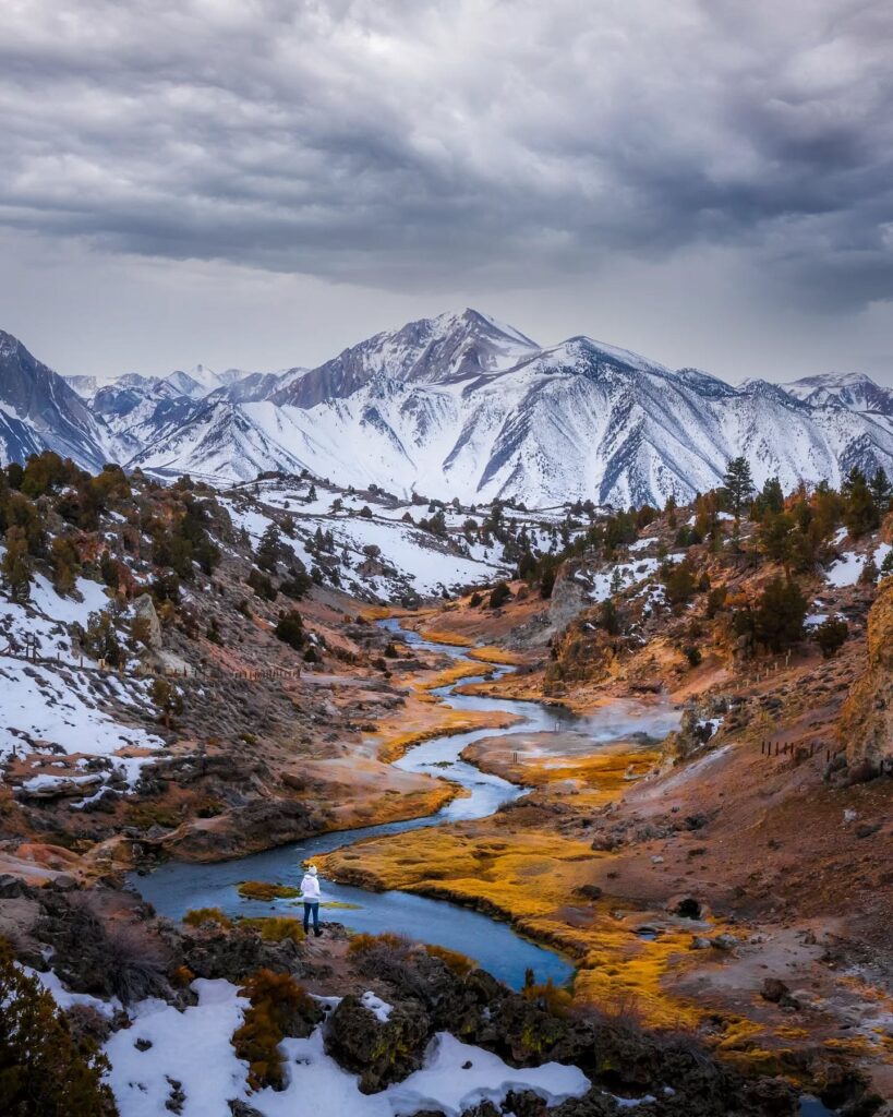 Steaming geothermal pools of Hot Creek with wooden trail and mountains