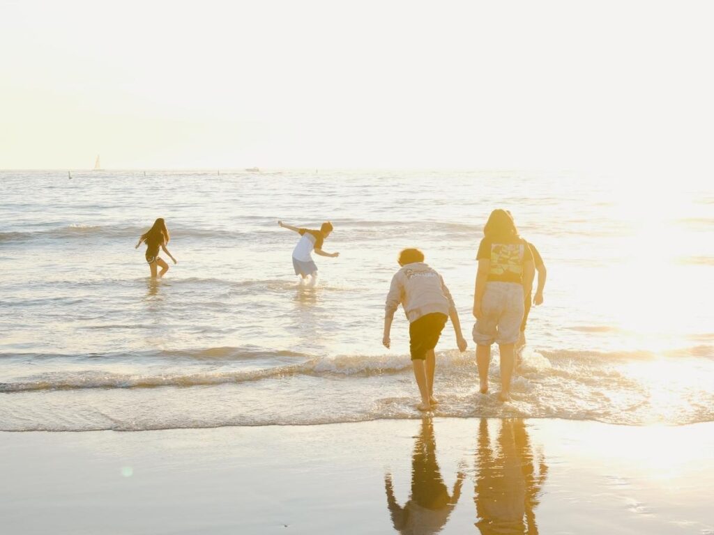 Visitors walking along Carmel Beach in the afternoon with gentle waves and wide shoreline.