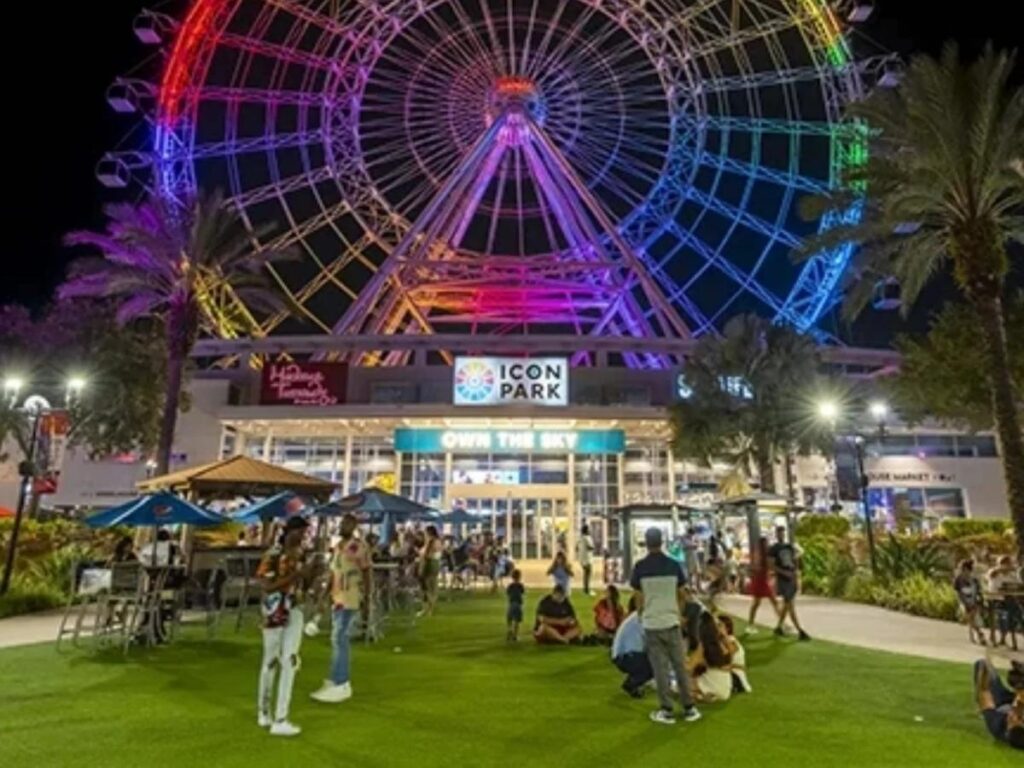 ICON Park in Orlando at night with lights, restaurants, and people strolling