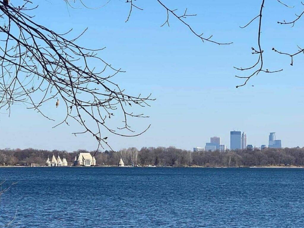 Sunset over Lake Harriet with people sitting quietly along the shoreline