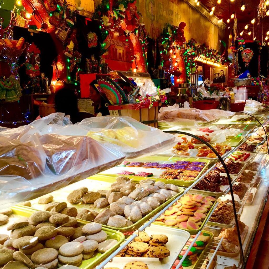 Interior of Mi Tierra Café with hanging lights, papel picado banners, and pastry display