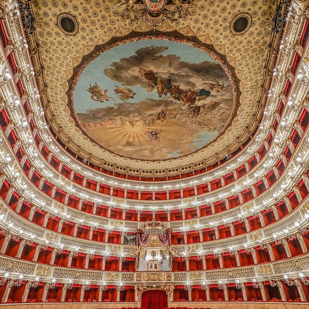 Ornate interior of Teatro di San Carlo with red velvet seats and a chandelier above the stage