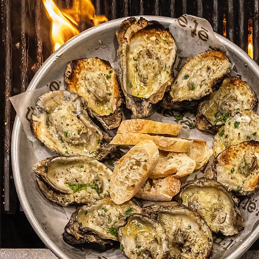 Chargrilled oysters served on a rustic plate at Ulele restaurant in Tampa