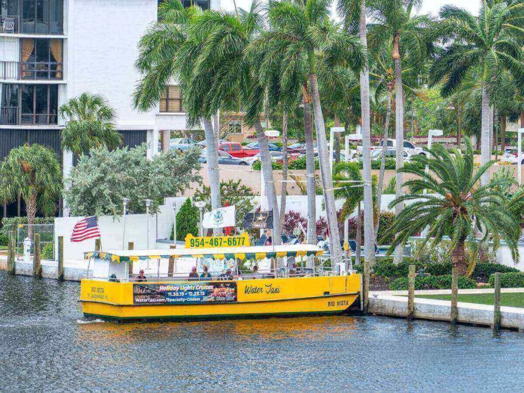 Fort Lauderdale water taxi cruising through city canals at sunset.