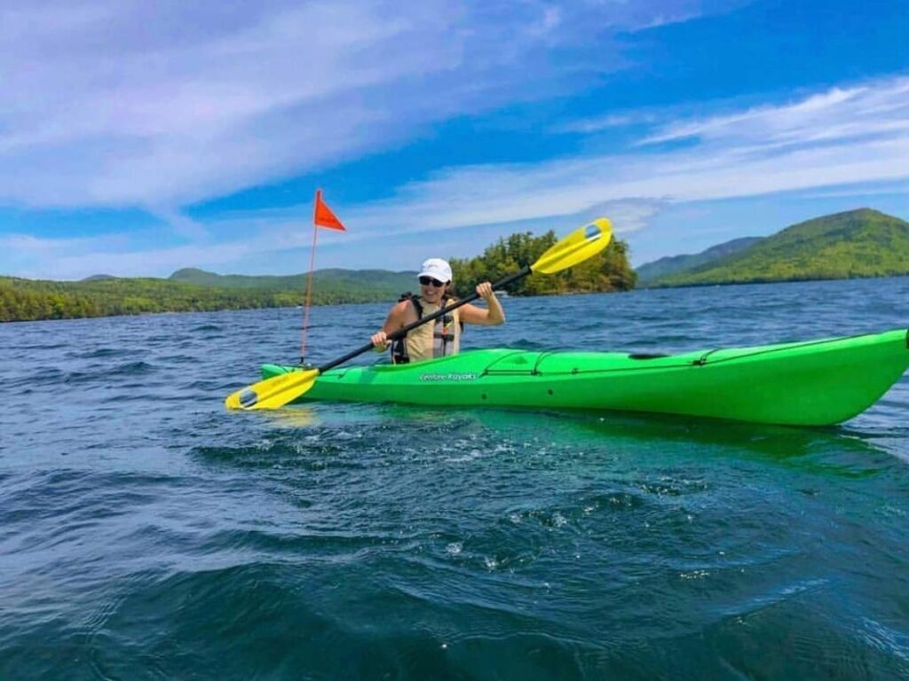 Kayaker on calm Lake George water during an early morning paddle