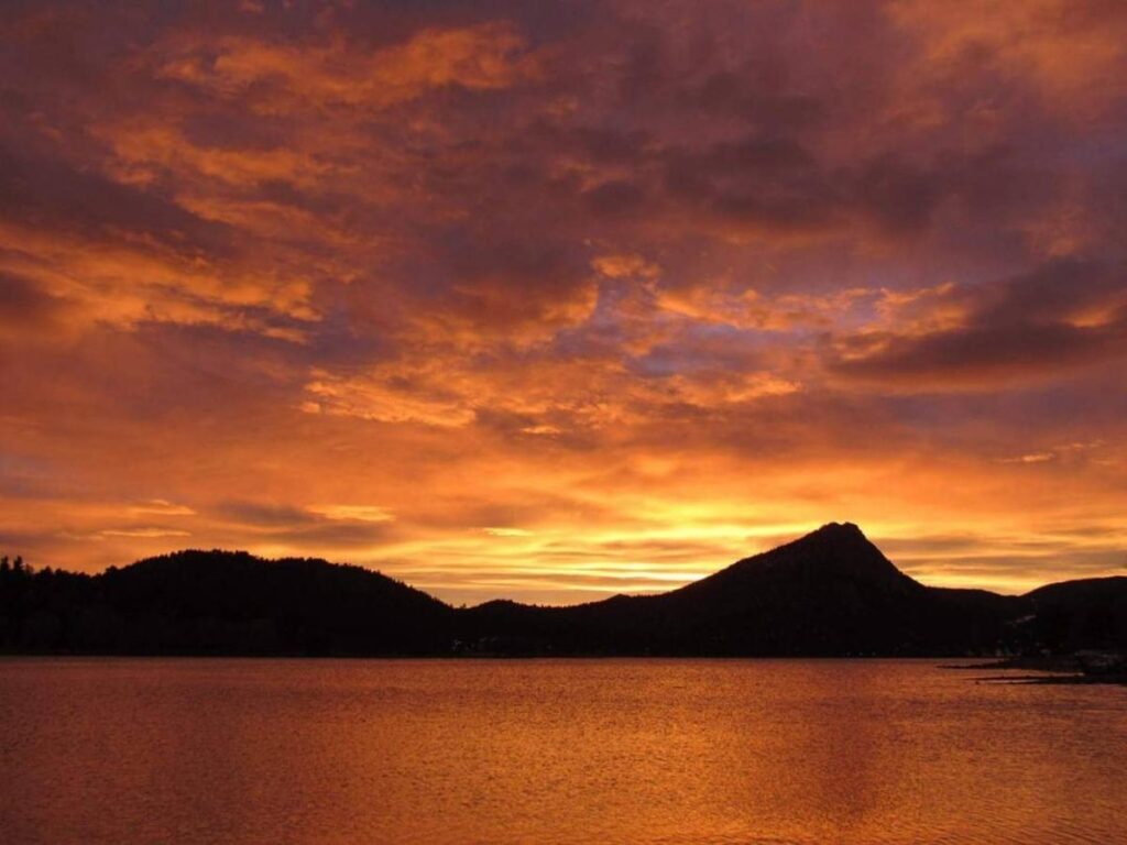 Sunrise over Lake Estes with calm water and mountain reflections.