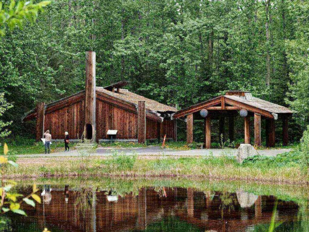 Traditional village structures along the lakeside walking path at the Alaska Native Heritage Center