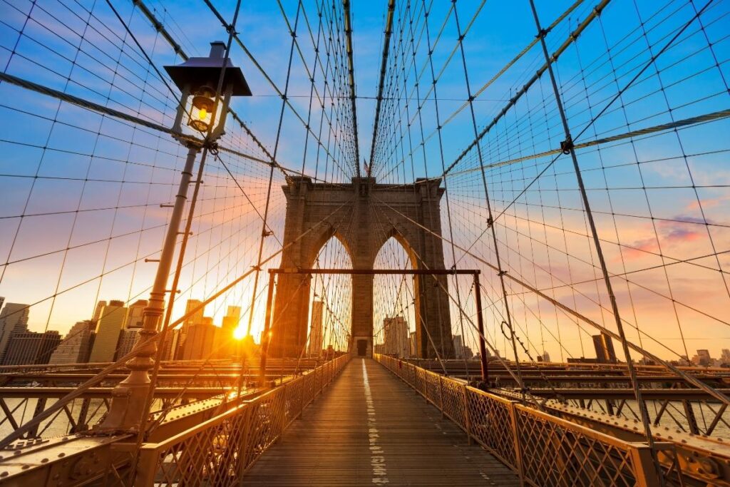 Tourists walking across the Brooklyn Bridge at sunrise