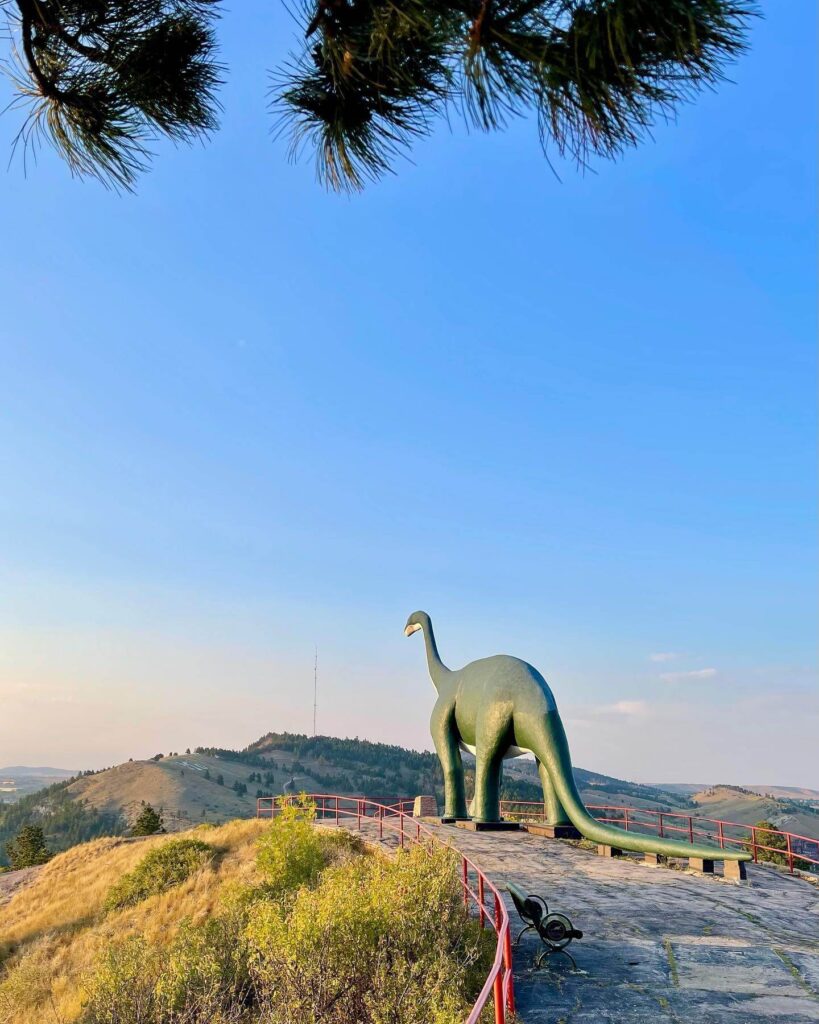 Green dinosaur sculpture overlooking Rapid City skyline at Dinosaur Park