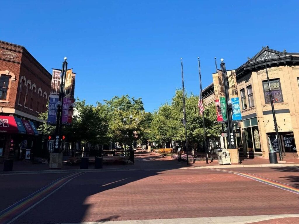 Street view in downtown Boulder with shops and mountain backdrop.