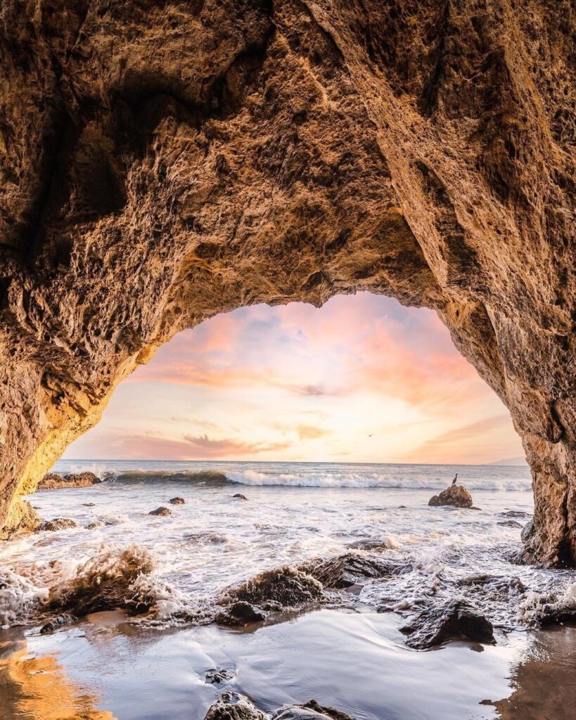 Rocky sea caves and sunset glow at El Matador Beach in Malibu, California