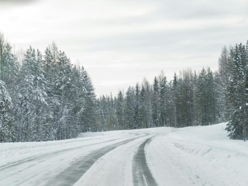 Snowy road outside Fairbanks with green northern lights glowing overhead