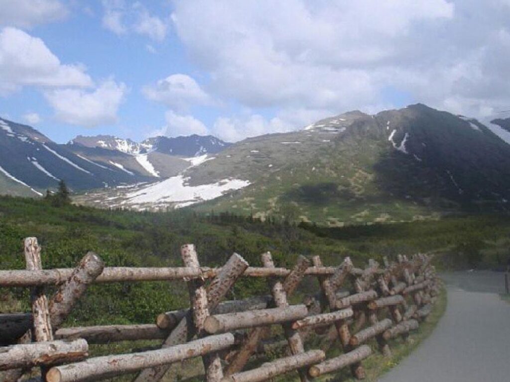 Hikers ascending the rocky section of Flattop Mountain with the city visible below