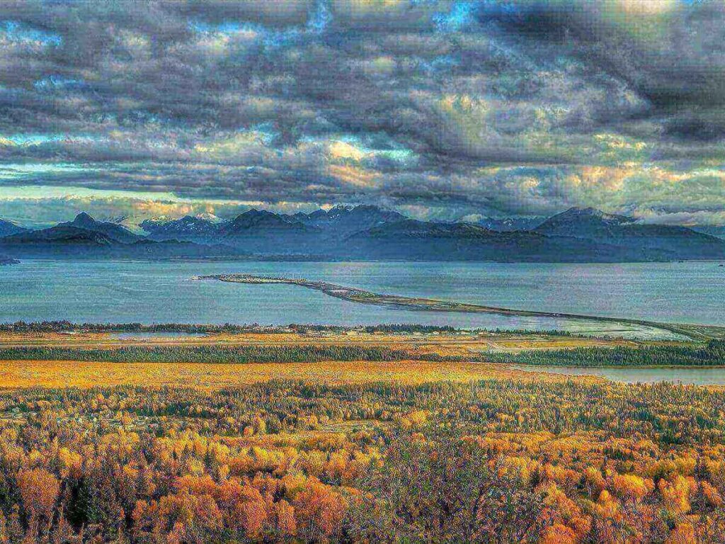 End of the road sign near Homer, Alaska with coastal scenery in the background