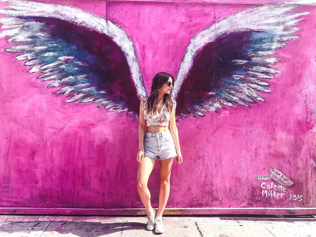Tourist taking photo in front of the pink wall mural on Melrose Avenue, Los Angeles