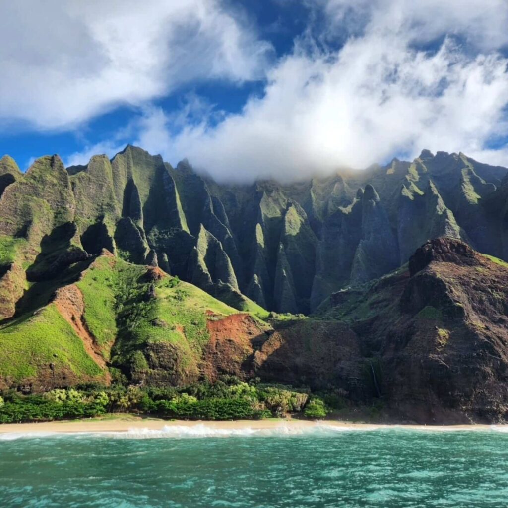 Sunset boat tour along the Nā Pali Coast with jagged cliffs and ocean spray
