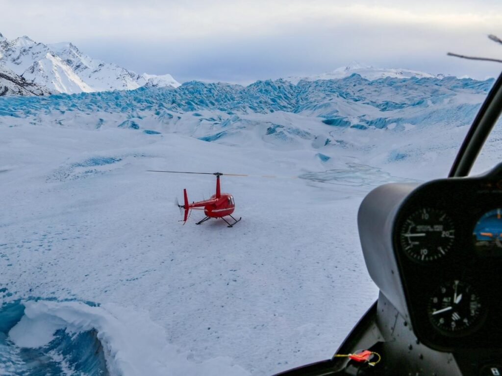 Small Rust’s Flying Service plane flying over blue glacier crevasses