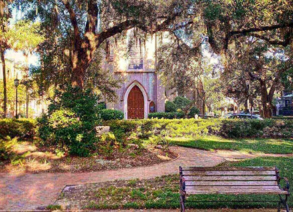A shaded bench in one of Savannah’s historic squares with people resting and reading