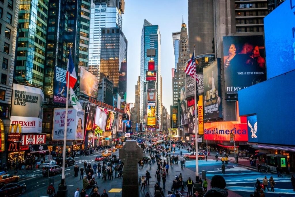 Times Square lit up at night with neon signs and people