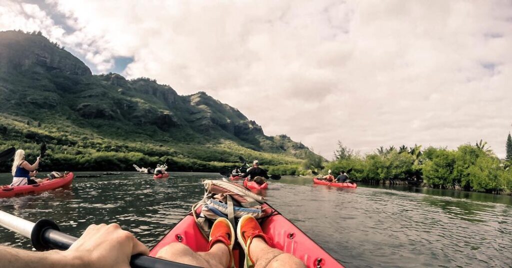 Kayakers paddling on the Wailua River through lush rainforest