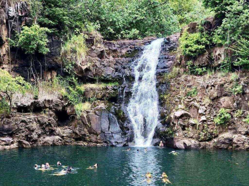 Visitors swimming at Waimea Falls in Oahu with lifeguards present
