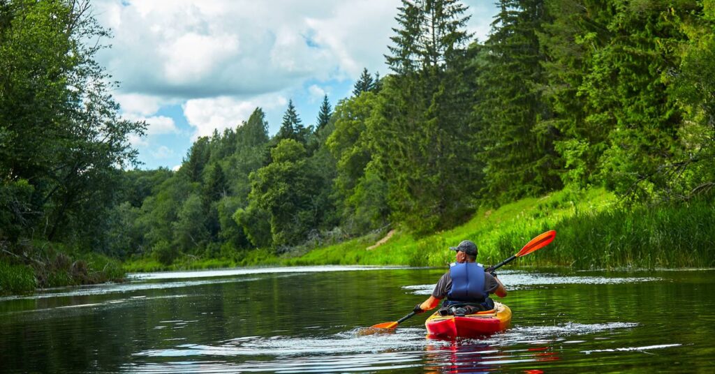 Person kayaking along Wailua River with jungle and waterfall ahead