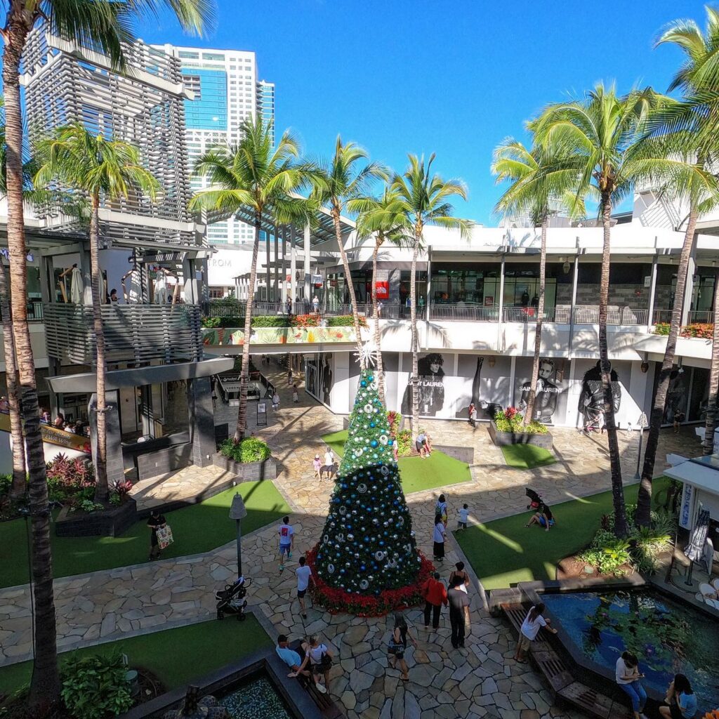 Shoppers walking through Ala Moana Center with palm trees and open sky