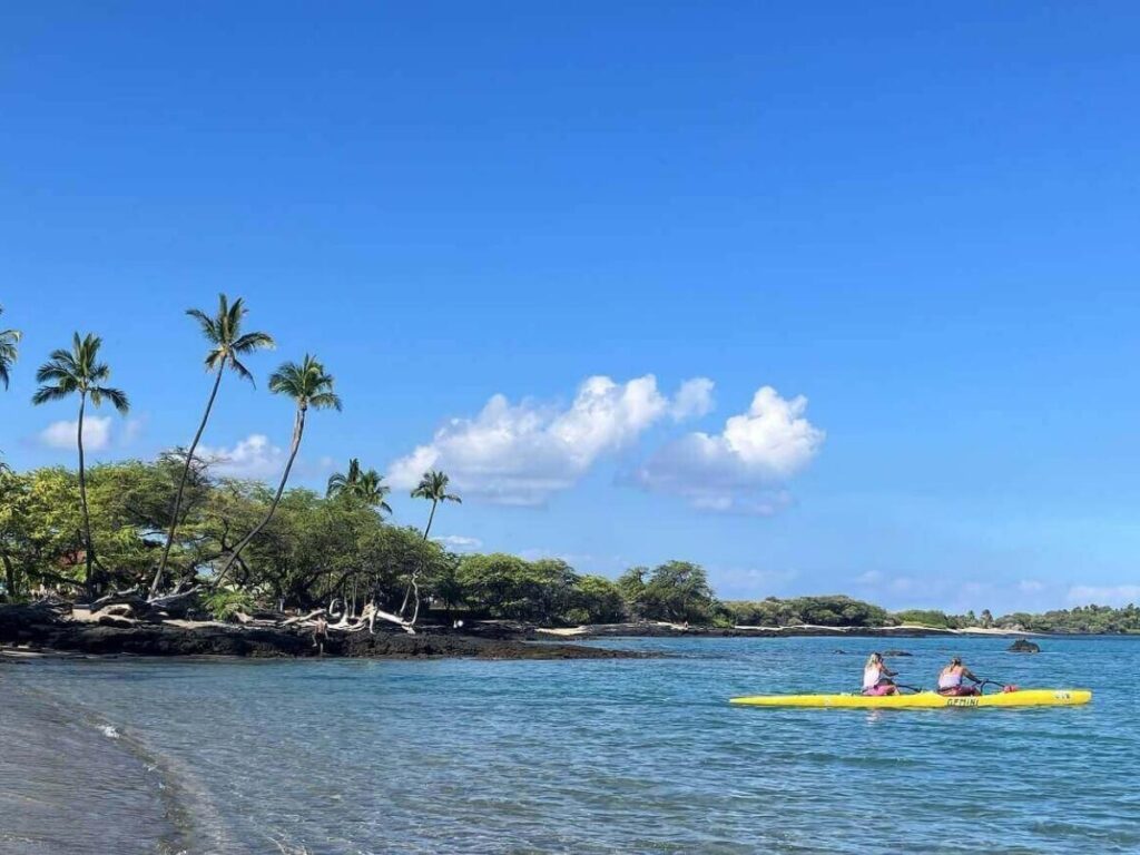Calm morning at Anaehoʻomalu Bay in Waikoloa with paddleboarders on clear water