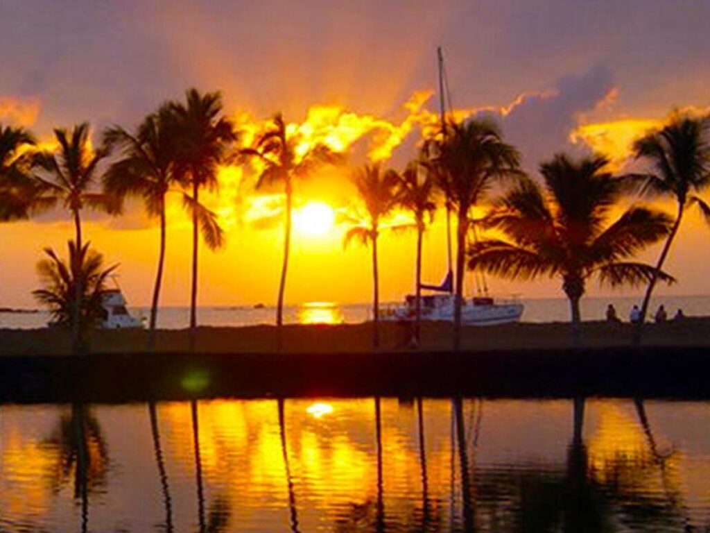 Sunset over Anaehoʻomalu Bay with palm trees along the shoreline