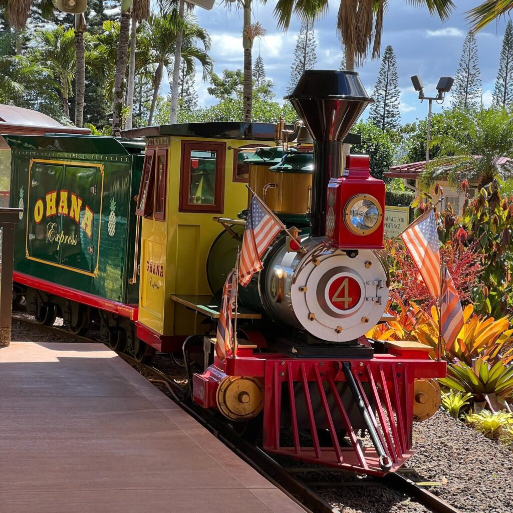 Bright yellow Pineapple Express train at Dole Plantation with greenery
