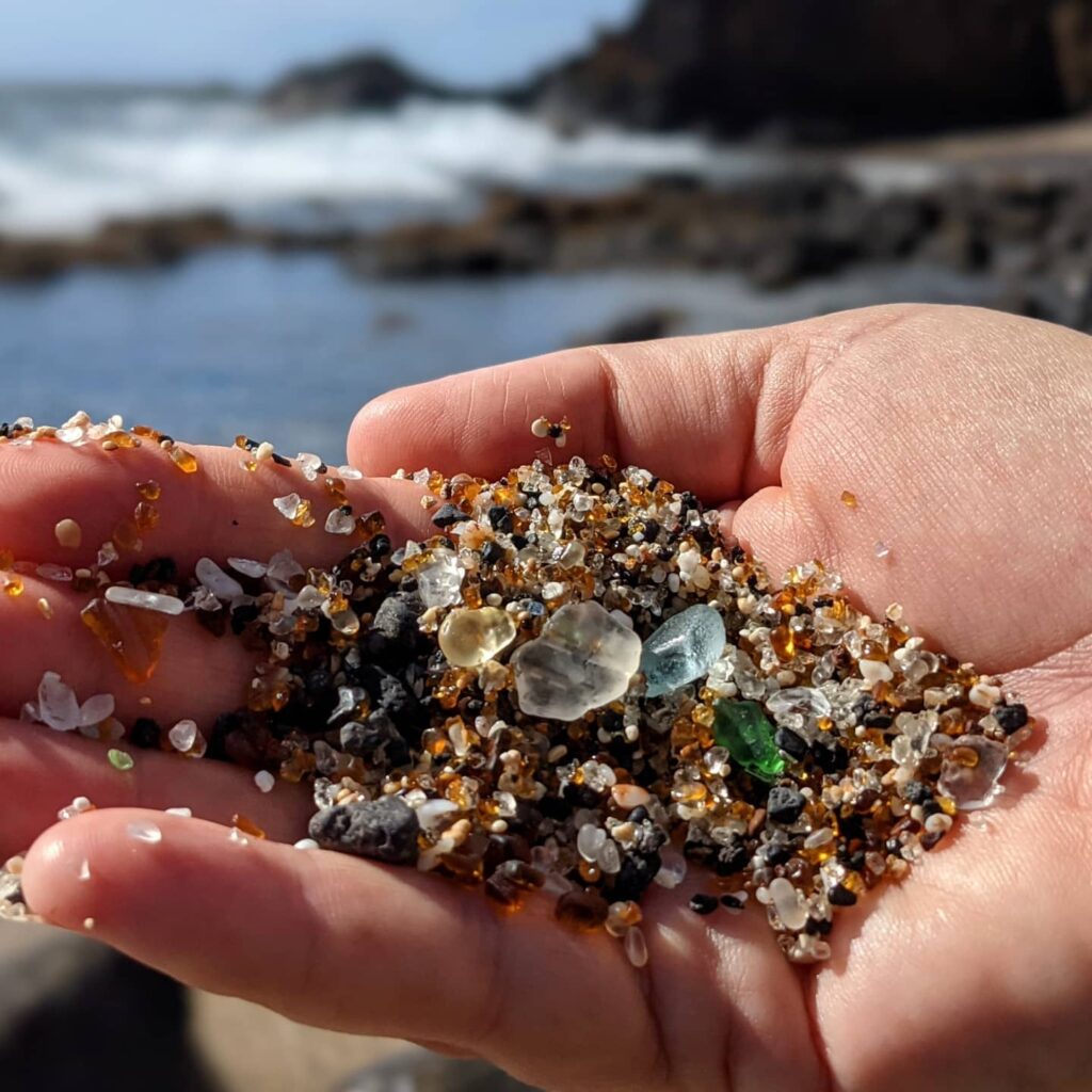 Close-up of colorful sea glass on black sand at Glass Beach
