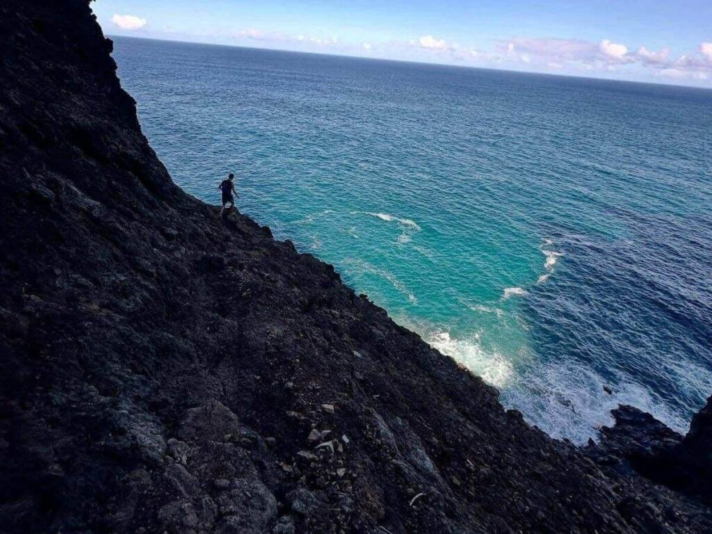 Hiker walking along a scenic trail on the Na Pali Coast in Kauai