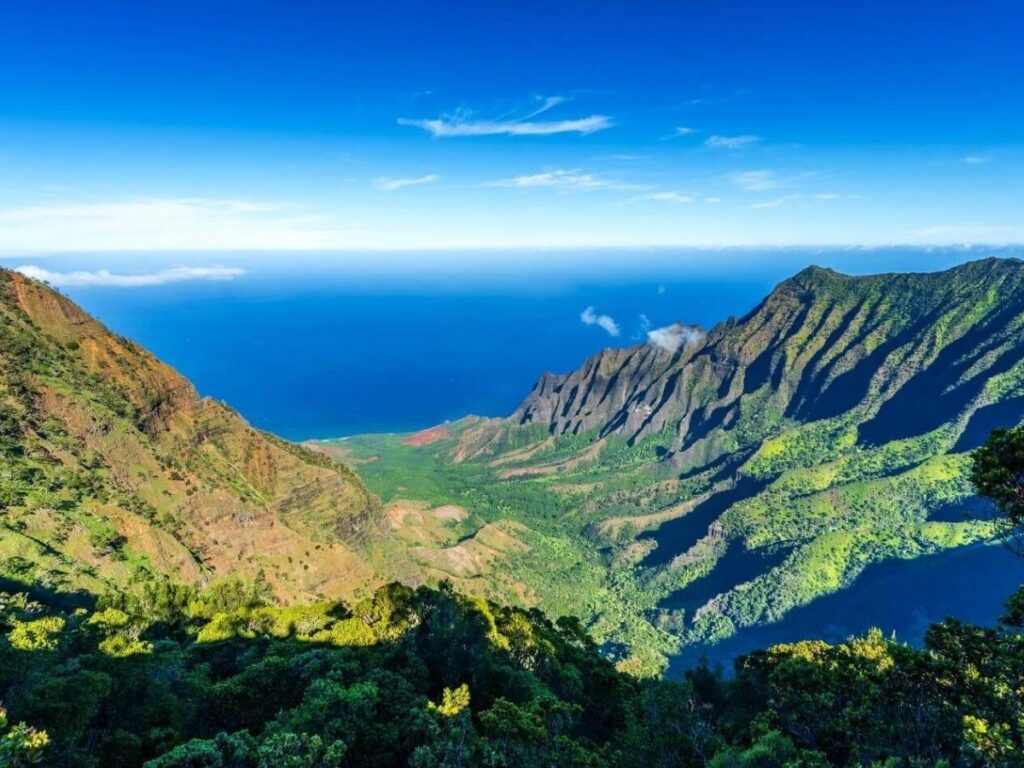Quiet coastline in Kauai state park with green mountains and blue ocean
