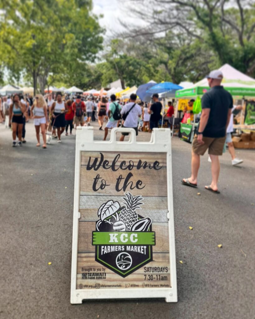 Outdoor market stalls with tropical fruit and local snacks at KCC Farmers Market