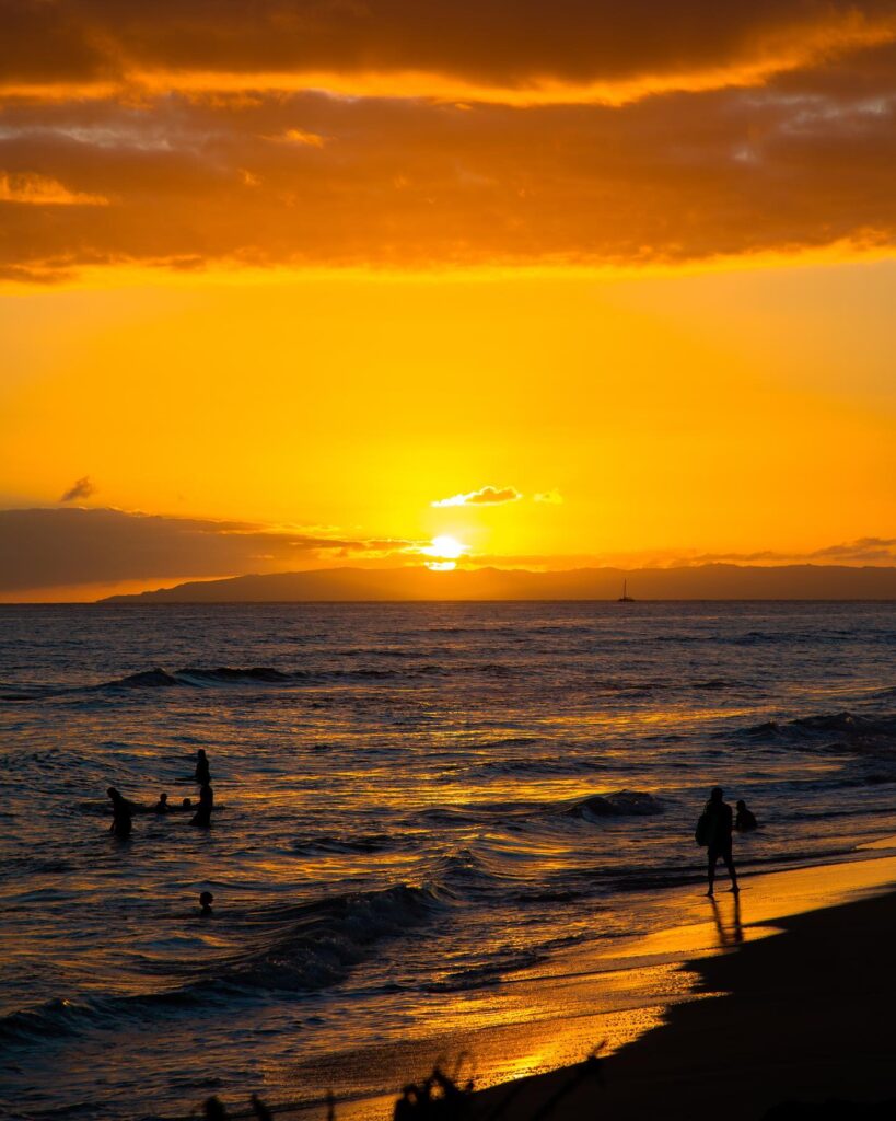 Orange sunset at Kekaha Beach with empty sand and rolling waves