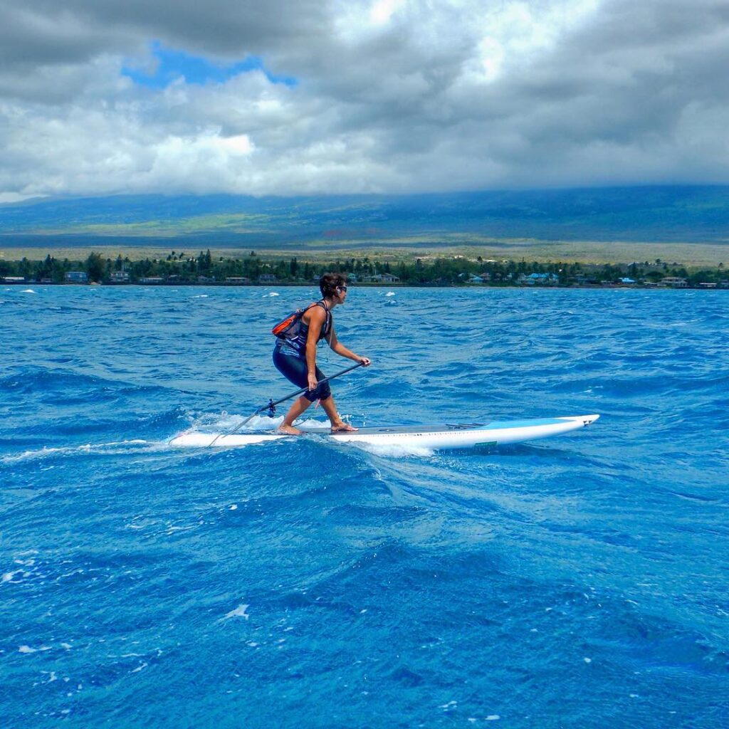 Paddleboarder gliding on calm, clear morning waters in Kihei